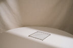 Metallic square object on a textured beige surface with soft shadows